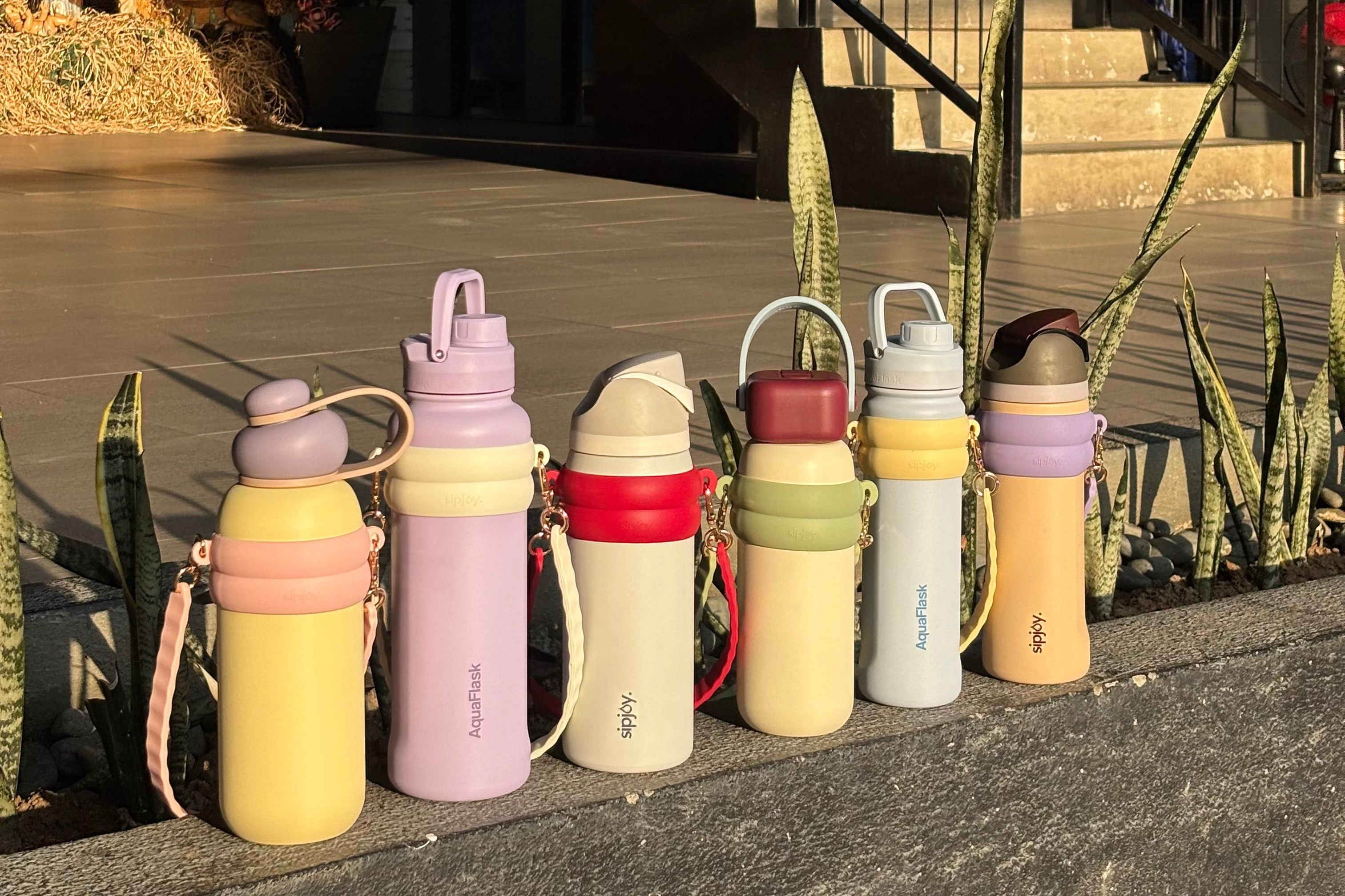Colorful water bottles with different designs on a concrete surface.